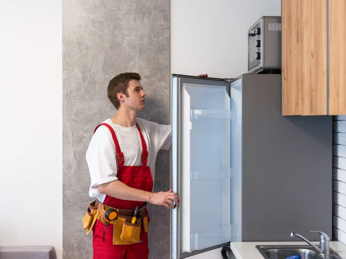 Technician inspecting a refrigerator for appliance repair